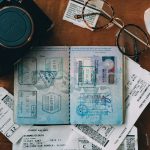 Open passport with visa stamps and travel documents on a desk